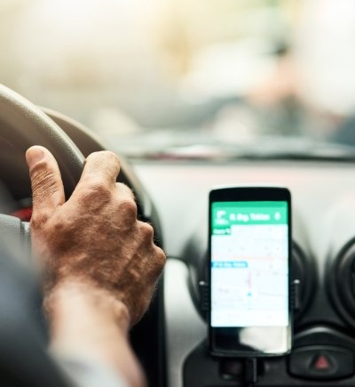 Closeup shot of a man using a phone to find directions while driving.